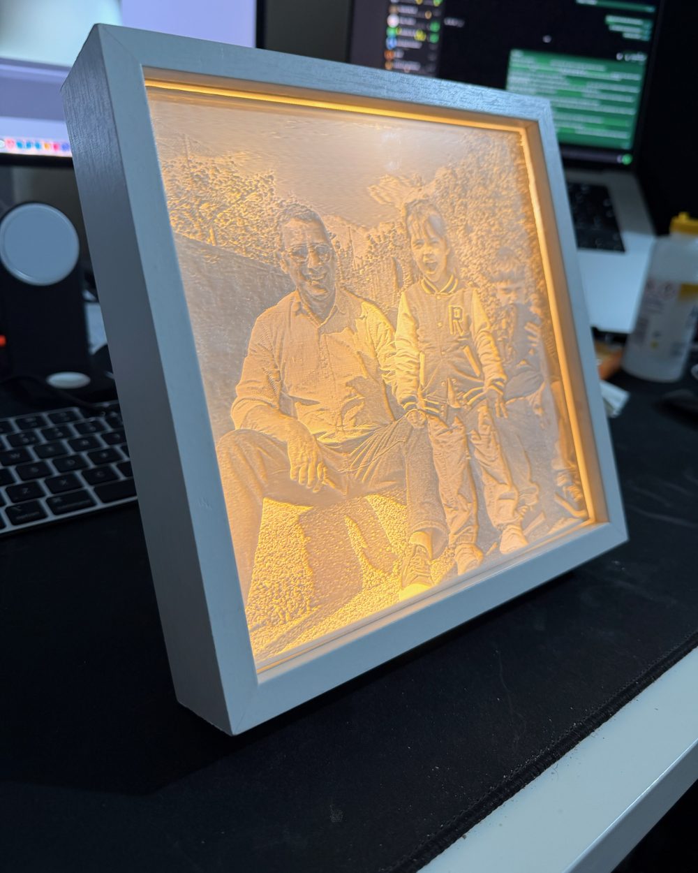Moldura com fotografia de família em relevo, iluminada por trás